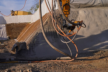 Spraying concrete for a wall to stabilize the excavation pit