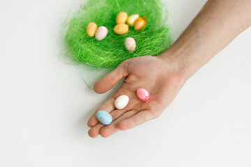 Easter toys. Easter toys with green leaves in the hands of a man. White background. Chicken eggs, twigs with green leaves on the hay. Easter holiday concept background.