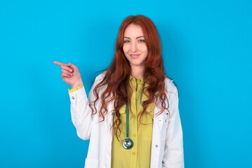 young doctor woman wearing medical uniform over blue background points to side on blank space demonstrates advertisement. People and promotion concept