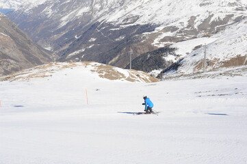 Skier skiing dowhill race on the piste in the mountains. Alps in winter, Europe.
