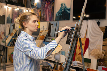 Fototapeta na wymiar The artist paints a picture in the studio.A young woman in the artist's creative studio