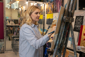 Art and culture. Portrait of a young woman who is painting a picture in the studio