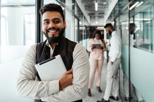 Young Indian Man In Suit Holding Tablet Computer At Office Corridor