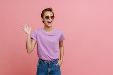 Young beautiful happy woman in sun glasses waving looking aside