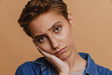 Portrait of young short-haired beautiful sad woman looking at camera