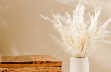 Wooden empty podium with vase and pampas grass, cozy shadows. Showcase for home product...