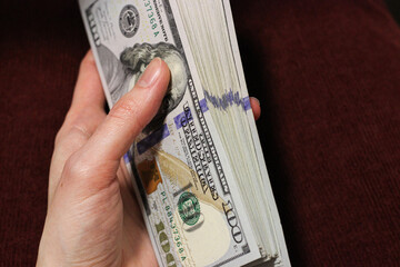 Woman hand is holding a stack of dollars. Bribery, corruption, salary, earning, bonus and savings...