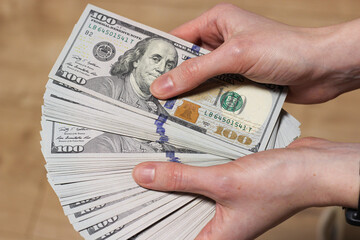 Woman hands is holding a stack of dollars. Bribery, corruption, salary, earning, bonus and savings...