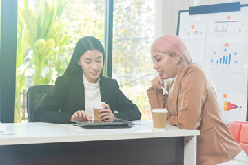 Two brunette business woman, talking, advising each other.