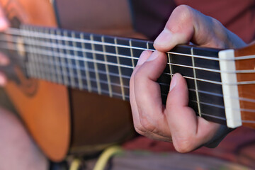 The man plays the guitar. Close-up of guitar strings.