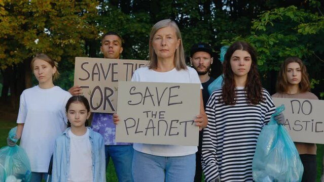 Group Multiethnic Eco Activist Standing in the Park with Garbage and Posters Save Our Planet, No Plastic, Save Forest. Diverse Volunteers Protesting Against Earth Garbage Pollution. Recycle Rubbish