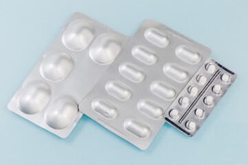 Blister packs with different pills on the blue surface