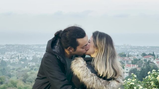 A lovely couple hugging and kissing behind Cyprus view in cloudy time.