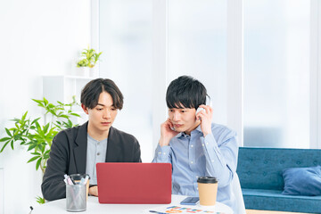 ノートパソコンを見る二人の若い男性
