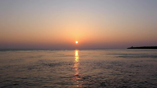 V&iacute;deo com o sol a por-se no horizonte com o reflexo do sol sobre o mar em movimento r&aacute;pido