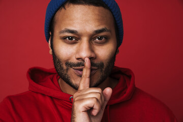 Indian man showing silence gesture isolated over red background