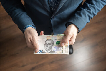 Well dressed man holding ukrainian paper currency Hryvnia banknotes