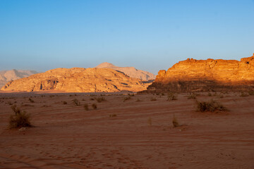 Jordan. Desert of Wadi Rum. Bizarre shapes of rocks in deserted desert. Landscape is similar to Martian landscapes. Sand is of beautiful pink color in rays of setting sun. Nature concept for design.