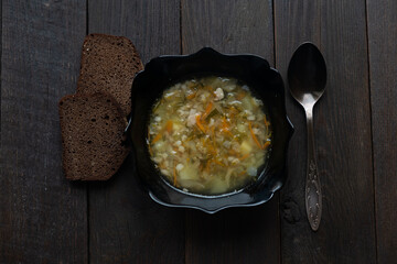 Appetizing traditional Russian dish Shchi - sour cabbage soup served in bowl, on a wooden table.