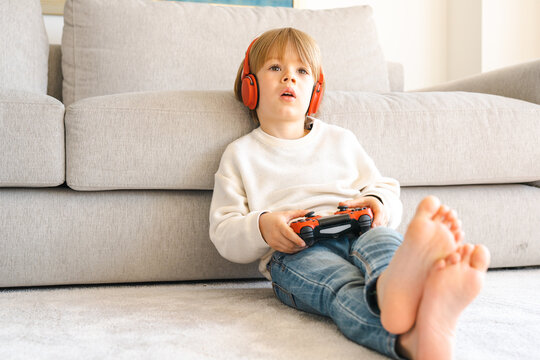 Little boy playing video game console using joystick or controller while sitting at home real people family leisure concept