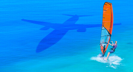 Travel concept - An passenger airplane shadow flying towards a tropical beach - Windsurfer surfing...
