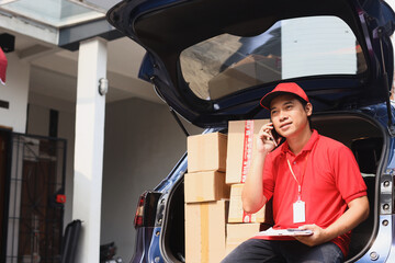 Unloading boxes in cargo van. The postman have a call checks the shipping address. Delivery of...