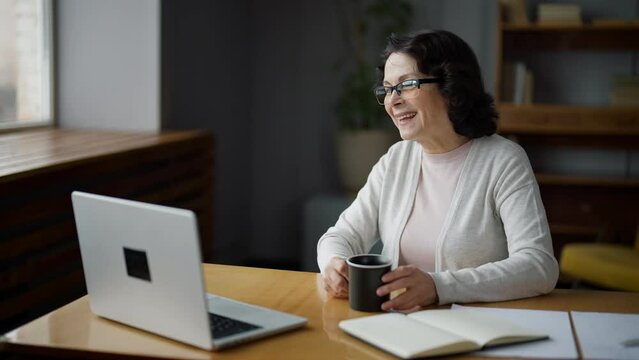Happy woman smiling and waving hand, sitting in home and talking on video call using laptop camera. Online meeting with professional psychologist, freelance work, communication with beloved relatives.