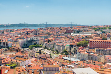 Fototapeta na wymiar Lisbon, Portugal skyline. Panoramic view of old town of Lisboa city with orange rooftops and bridge on Tagus river.