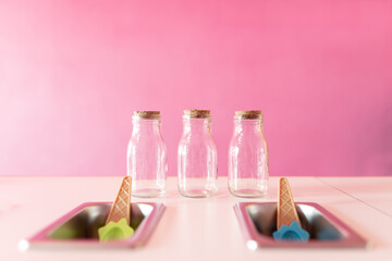 Three empty jars ready to prepare ice-cream rolls on a counter next to topping trays