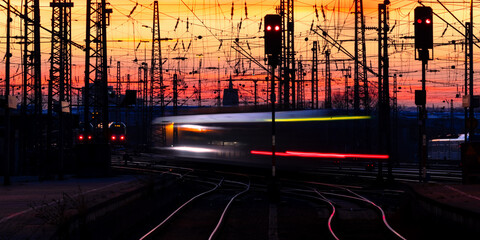 Trains in motion at Dortmund station in warm evening light. Curved main line railway tracks...