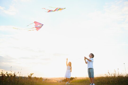 Children launch a kite in the field at sunset