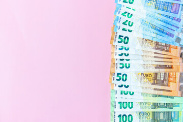Background of mixed euro banknotes, One hundred euros, fifty euros, twenty euros on pink backgrond, Pile of banknotes on pink background, with copy space.