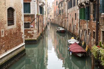 Boats and reflections on canals of Venice in a cloudy winter day during 2023 Venice Carnival celebrations