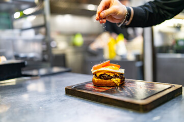 chef hand cooking cheeseburger on restaurant kitchen
