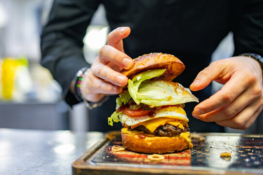 chef hand cooking cheeseburger on restaurant kitchen