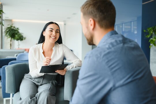 Business concept. Young dark-haired woman sitting in front of mature cheerful office manager on job interview, having relaxing talk about her experience and study degree.