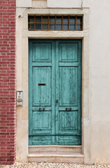 Old scratched turquoise wooden entrance door of a historic building