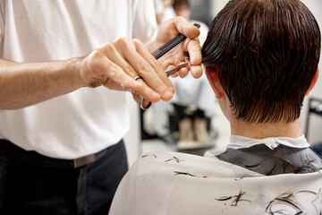 young caucasian man getting haircut by professional male hairstylist