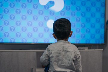 Little boy gawking at the TV in front of the big screen.