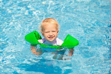 Fototapeta na wymiar Baby with inflatable armbands in swimming pool.