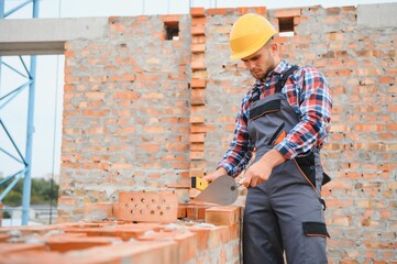 Busy with brick wall. Construction worker in uniform and safety equipment have job on building.