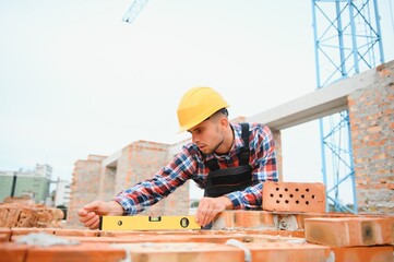 Installing brick wall. Construction worker in uniform and safety equipment have job on building