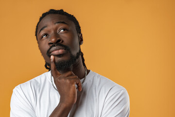 Young african guy thinking about something over yellow background