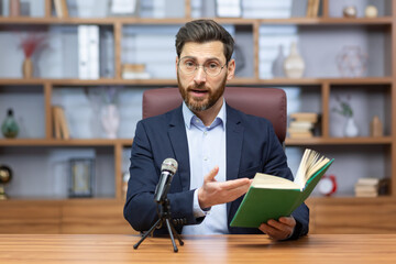 Senior mature pastor reading bible book online, man looking at camera sitting in home office and...