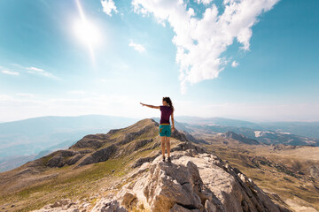 Obraz premium the traveler stands on the top of the mountain. the girl goes to the mountains.