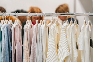 Close-up of womens Knitwear in light colors hanging in row in clothes store. Shopping