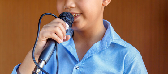 A boy with a microphone singing with a very determined look,Close up