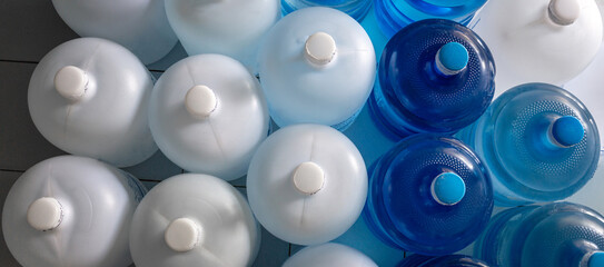 Top view of plastic big bottles or white and blue gallons of purified drinking water inside the...
