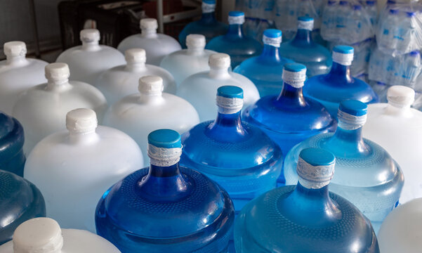 Plastic big bottles or white and blue gallons of purified drinking water inside the production line. Water drink factory