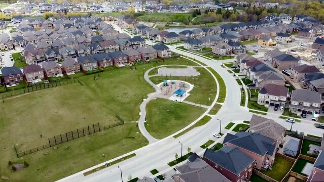 Drone flying towards a Kleinburg neighborhood park and playground in spring.